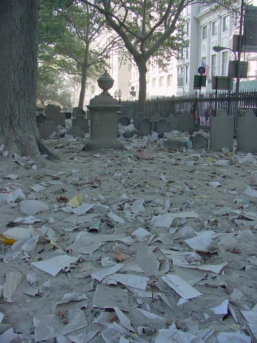Papers, debris and concrete dust fill a cemetery