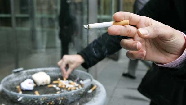 Employees smoke outside the entrance of an office building in the complex in Paris, Wednesday, Jan. 31, 2007. (AP Photo/Jacques Brinon)