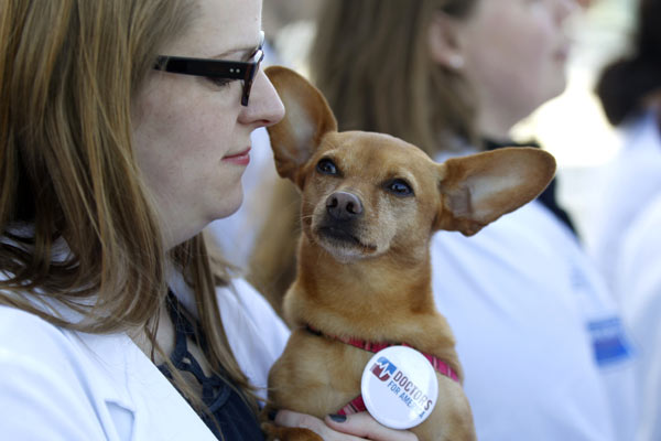 Georgetown University Medical Student Kate Prather, who supports the health care reform law signed by President Barack Obama, holds her dog Ellie as she stands in front of the Supreme Court in Washington.