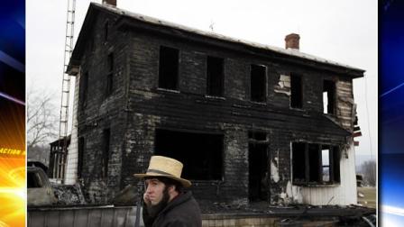 A neighbor stands near the fire ravaged farmhouse of Theodore and Janelle Clouse Wednesday, March 9, 2011, in Loysville Pa. Seven Clouse children including a 7-month-old infant, perished in a fast-moving fire at the home early Wednesday morning, March 9, 2011, while their mother milked cows and their father dozed in a milk truck down the road.