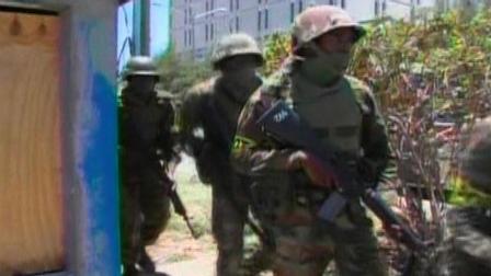 This frame grab from video provided by APTN shows soldiers on guard in Kingston, Jamaica, Monday, May 24, 2010. Thousands of armed police and soldiers barged past barricades into the capitals most violent slums.