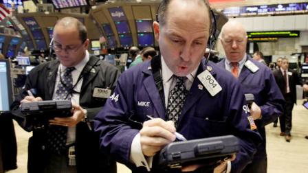 In this Jan. 31, 2011 photo, trader Michael Urkonis, center, uses his handheld device as he works on the floor of the New York Stock Exchange. (AP Photo/Richard Drew)
