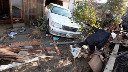 A resident of the seaside town of Yotsukura, northern Japan, clears debris from his homes Monday, March 14, 2011, three days after a giant quake and tsunami struck the countrys northeastern coast. (AP Photo/Mark Baker) 