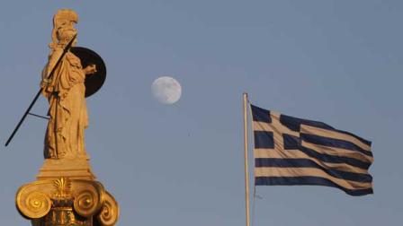 The moon rises behind the 19th century statue of the ancient goddess Athena as a Greek flag billows at the Athens Academy in Athens, Tuesday, July 12, 2011.