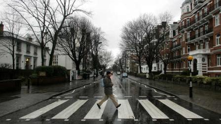 In this file photo taken Feb. 16, 2010, a man walks on the zebra crossing made famous from the album cover of The Beatles Abbey Road in front of Abbey Road Studios, seen at left, in London. EMI Group Ltd., home of The Beatles, Coldplay and Katy Perry, is being sold in two parts for $4.1 billion.