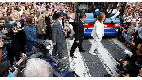 A tribute band dressed as members of the British band, the Beatles, walk across the famous pedestrian crossing on Abbey Road, in London, in a recreation of the Beatles Abbey Road album cover as hundreds of people gathered to mark the 40th anniversary of the album, Saturday, Aug. 8, 2009. (AP Photo/Sang Tan)