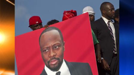 A supporter holds a portrait of Haitian-born singer Wyclef Jean as Wyclef, right, leaves the electoral office after submitting the paperwork to run for president of Haiti in the next elections in Port-au-Prince, Haiti, Thursday, Aug. 5, 2010. (AP Photo/Ramon Espinosa)