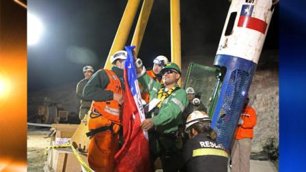 In this photo released by the Chilean government, miner Jose Ojeda holds a Chilean flag as he exits the capsule during his rescue from the collapsed San Jose gold and copper mine where he had been trapped with 32 other miners for over two months near Copiapo, Chile, early Wednesday Oct. 13, 2010. (AP Photo/Hugo Infante, Chilean government)