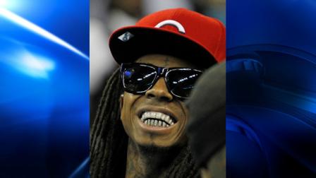 Entertainer Lil Wayne smiles before the start of the second half of an NBA basketball game between New Orleans Hornets and the Miami Heat in New Orleans, Friday, Nov. 5, 2010. (AP Photo/Bill Haber)