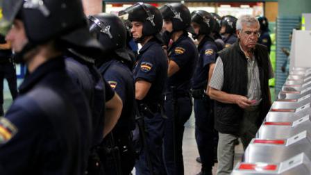 A passenger accesses the railway station as riot police stand guard in Madrid, during a partial national rail strike, Monday, Sept. 17, 2012. Hundreds of Spanish train services have been canceled as rail and subway workers staged strikes to protest wage cuts and reforms. State rail company RENFE said Monday it had canceled some 300 high-speed and intercity trains. It said minimum services agreed with labor unions meant that more than 50 percent of trains would run throughout the day. (AP Photo/Andres Kudacki)