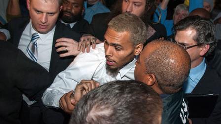Singer Chris Brown is surrounded by bodyguards as he departs the H. Carl Moultriel courthouse Monday, Oct. 28, 2013, in Washington. A charge against the Grammy Award-winning R&B singer has been reduced to a misdemeanor and he was ordered released after his arrest Sunday following an altercation outside a Washington hotel.