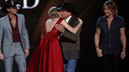 Taylor Swift, second left, is congratulated by presenter George Strait as she accepts the Pinnacle award at the 47th annual CMA Awards at Bridgestone Arena on Wednesday, Nov. 6, 2013, in Nashville, Tenn. Looking on at left is presenter Tim McGraw and at right Keith Urban. (Photo by Wade Payne/Invision/AP)