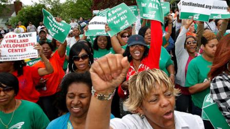 FILE - In this April 26, 2011 file photo, worker Marion Gaines, front right, reacts with others in a large gathering of workers and supporters as they listen to Rev. Al Sharpton, in Vineland, N.J., outside the Vineland Development Center which houses 350 women with severe disabilities. New Jersey Gov. Chris Christies proposed budget calls for saving $1.6 million a year by closing the center, and Sharpton urged the workers in Vineland to demand justice for themselves and the centers residents. The decision to close the center has stirred emotional debate. (AP Photo/Mel Evans, File)