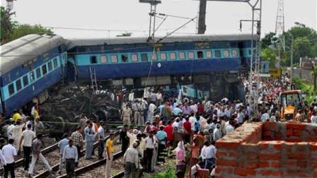 People look at the wreckage of the Kalka Mail passenger train which derailed near the town of Fatehpur in Uttar Pradesh state, India, Sunday, July 10, 2011. The packed train was on its way to New Delhi from Howrah, a station near Kolkata, when its 12 coaches and the engine jumped the tracks. At least seven people died and more than 100 are injured, officials said.