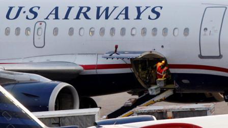 In this July 19, 2011 photo, baggage is unloaded from a U.S. Airways jet at Logan International Airport in Boston. US Airways Group Inc. said Thursday, July 21, its second-quarter profit fell 67 percent as fuel prices jumped. (AP Photo/Elise Amendola)