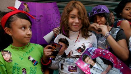 Fans hold pictures of pop star Justin Bieber near Mexico Citys main historic plaza, the Zocalo, Sunday, June 10, 2012. The Beliebers have arrived in the chaotic streets of Mexico City, adolescents in purple and white and braving two nights on roach-infested sidewalks for a chance to be closest to the stage when teenage superstar Justin Bieber puts on a free concert Monday evening on the capitals vast central plaza.(AP Photo/Marco Ugarte)
