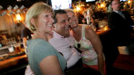 New Jersey Gov. Chris Christie poses for photos with patrons at The Ark pub and eatery in Point Pleasant Beach, N.J., Friday, Sep. 2, 2011. As New Jersey adds up its Irene-related damage totals, Christie, who a week ago ordered people off the beach, urged people to come to the states beaches this Labor Day weekend to support the local economy. (AP Photo/Rich Schultz)