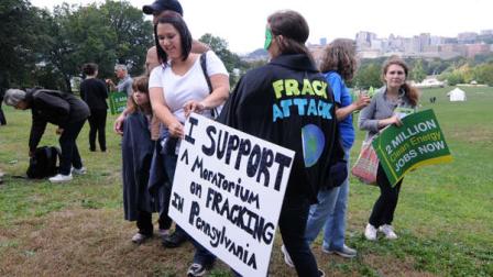 Melissa Waldron, left, holds a sign supporting the moratorium as participants rallied during a global Frackdown Day at Schenley Park in Pittsburgh, Saturday, Sept. 22, 2012. (AP Photo/John Heller)