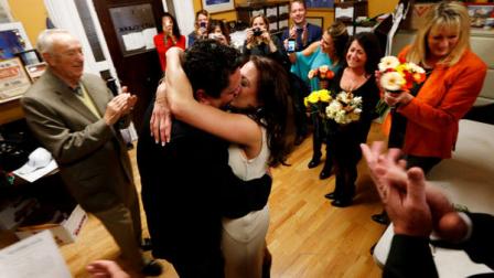 Thomas Carroll, 48, of Hoboken, N.J., center left, gives a kiss to his new bride, Stephanie McClure, of Smyrna, Ga., as a small party cheers for them moments after they were married by city clerk James Farina at Hoboken City Hall, Tuesday, Nov. 6, 2012, in Hoboken, N.J. The couple was scheduled to get married on Nov. 3, in Point Pleasant, N.J., but Superstorm Sandy washed away their wedding. Meanwhile, residents of Hoboken voted in the presidential election on Election Day in a polling place located in the adjacent room. (AP Photo/Julio Cortez)