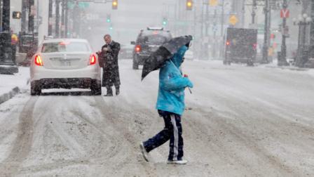 A man uses an umbrella to ward off snow as he crosses a street in Denvers financial district on Tuesday, April 9, 2013. A blizzard forecast for the area did not materialize. Instead as much as four inches of snow could fall on the Mile High City. (AP Photo/Ed Andrieski)