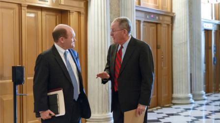 Sen. Chris Coons, D-Del., left, and Sen. Lamar Alexander, R-Tenn., right, speak in the corridor just off the Senate floor as lawmakers wait for a vote on the defense bill, at the Capitol in Washington, Thursday, Dec. 19, 2013. (AP Photo/J. Scott Applewhite)