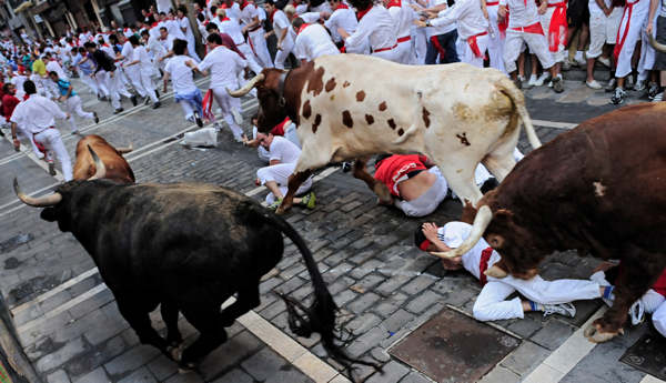 Revelers run in front of a Jandilla ranch...