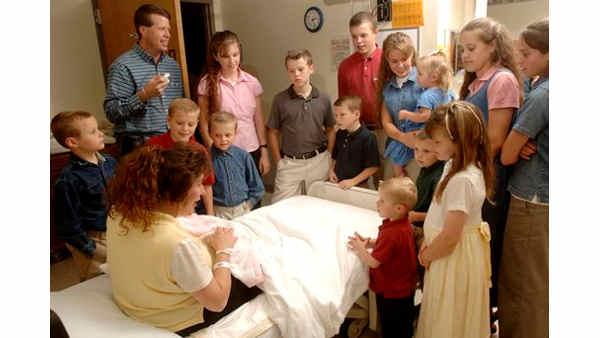 Michelle Duggar, left, is surrounded by her children and husband Jim Bob, top left, while she holds her newborn daughter, Jennifer Danielle, Thursday, Aug. 2, 2007 in Rogers, Ark. Jennifer Danielle was born at 10:01 a.m., weighed 8 lbs 8 oz, was 21 inches long, and is the 17th child born to Michelle and Jim Bob Duggar. (AP Photo/Beth Hall)