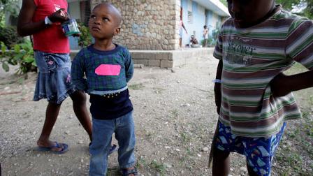 A boy, with a pink tape on his shirt that previously had his name written on it, and who was part of the group of children that U.S. Baptists were trying to take out of Haiti, looks at other kids playing at an orphanage run by Austrian-based SOS Childrens Villages in Port-au-Prince, Sunday, Jan. 31, 2010. Ten Americans were detained by Haitian police on Saturday as they tried to bus 33 children across the border into the Dominican Republic, allegedly without proper documents. (AP Photo/Andres Leighton)