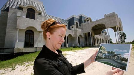 In a Friday, June 11, 2010 photo, realtor Lorraine Barrett looks at a rendering of what the unfinished mansion nicknamed Versailles will look like when completed, in Windermere, Fla. The mansion is currently up for sale as is by owner and timeshare tycoon David Siegel. (AP Photo/John Raoux)