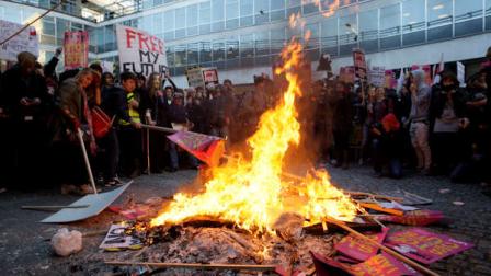 Demonstrators burn protest banners outside Millbank Tower, housing the headquarters of the Conservative Party, during a protest in London Wednesday Nov. 10, 2010, against an increase in university tuition fees. Organizers said 50,000 students, lecturers and supporters were demonstrating against plans to raise the cost of studying at a university to 9,000 pounds ($14,000) a year - three times the current rate.(AP Photo/Sang Tan)