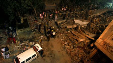 An ambulance stands at the scene where a building collapsed in New Delhi, India, late Monday, Nov. 15, 2010. The four-story building collapsed in the congested neighborhood in New Delhi Monday, killing over two dozen people and injuring scores of others, a top police official said. (AP Photo/ Mustafa Quraishi)