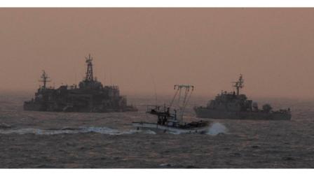 A South Korean fishing boat sails by a South Korean navy facility and navy ship near Yeonpyeong island, South Korea, Sunday, Dec. 19, 2010. South Korea said Saturday it would go ahead with artillery drills on the border island shelled by North Korea last month despite Pyongyangs threat to retaliate again, as Russia and China expressed concerns over tension on the volatile peninsula. (AP Photo/Ahn Young-joon)