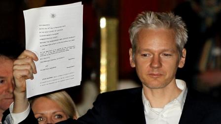 WikiLeaks founder Julian Assange holds up a court document for the media after he was released on bail, outside the High Court, London, Thursday, Dec. 16, 2010. WikiLeaks founder Julian Assange has been released on bail following a week of legal drama over his extradition.