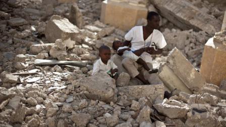 A man with two children sits in the rubble of the earthquake damaged Cathedral during a mass in Port-au-Prince, Haiti, Wednesday Jan. 12, 2011. Wednesday marks the one year anniversary since Haitis magnitude-7.0 earthquake that devastated the capital and is estimated to have killed more than 230,000 people and left millions homeless. (AP Photo/Ramon Espinosa)