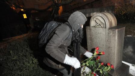Edgar Allan Poe fan Cynthia Pelayo of Chicago lays roses near the authors original burial place Wednesday, Jan. 19, 2011 at Westminster Church and Cemetary in Baltimore. A mysterious visitor, who has annually left roses and cognac there in the early hours of Jan. 19, Poes birthday, was a no-show for the second consecutive year.
