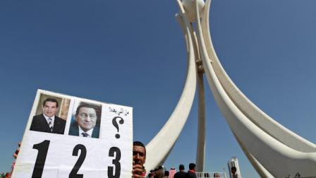 A Bahraini anti-government protester holds up a banner with pictures of former Tunisian president Zine El Abidine Ben Ali, left, and former Egyptian president Hosni Mubarak, center, and says in Arabic who is next? at the Pearl roundabout in Manama, Bahrain, Sunday, Feb. 20, 2011. Bahrains opposition leaders gathered Sunday to examine offers for talks by Bahrains rulers after nearly a week of protests and deadly clashes that have sharply divided the strategic Gulf nation. (AP Photo/Hassan Ammar)