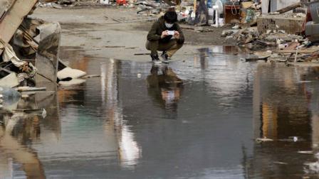 A man takes a picture in the debris at a March 11 earthquake and tsunami-destroyed town of Kesennuma, Miyagi Prefecture, Japan, Saturday, April 2, 2011. (AP Photo/Lee Jin-man)