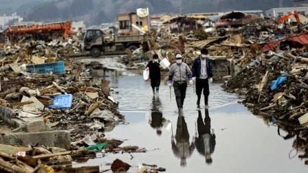 A Japanese family walks along the flooded street at an area devastated by the March 11 earthquake and tsunami in the port town of Kesennuma, Miyagi prefecture, Japan, on Monday, April 11, 2011. Exactly a month ago today a massive earthquake and tsunami ravaged Japans northeastern coastal region. (AP Photo/Sergey Ponomarev)