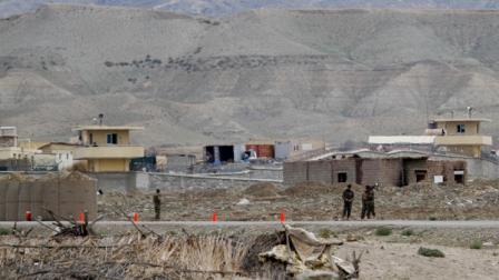 Afghan army forces stand guard as the view the military base is seen in the background after suicide bomber wearing an Afghan security-forces uniform has blew himself up at the entrance to the military base in eastern province of Laghman, killing NATO and Afghan soldiers, east of Kabul, Afghanistan, Saturday, April 16, 2011. (AP Photo/Rahmat Gul)
