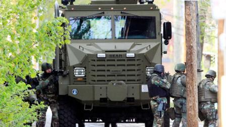 The state police SWAT team has guns drawn during a police standoff with an armed man, Friday, May 6, 2011 in Manchester, N.H. Police in New Hampshire say they have communicated with an armed man in Manchester who is holed up in an apartment building. The standoff that began Thursday night has led to the closure of an estimated eight-block section of Manchester and the Friday closing of the West High School. (AP Photo/Jim Cole)
