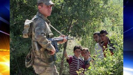 A Turkish soldier stands by as a group of Syrians wait inside Syria for the authorization to enter Turkey near the Turkish village of Guvecci in Hatay province, Turkey, which borders Syria Thursday, June 9, 2011.
