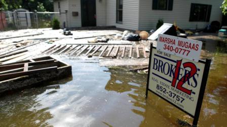 Debris floats up to a home for sale from the Souris River flood waters in the Minot, N.D., neighborhood of Oak Park Saturday, June 25, 2011. (AP Photo/Charles Rex Arbogast)