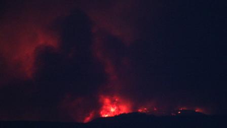 A wildfire burning in the Jemez Mountains skips across a ridge of trees as seen Rio Rancho, N.M., on Sunday, June 26, 2011. The fast-moving wildfire forced officials at the Los Alamos National Laboratory to close the site Monday as residents nearby evacuate their homes. (AP Photo/Susan Montoya Bryan)
