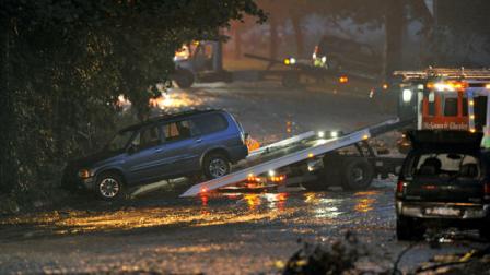 Workers clear vehicles from the scene of flash flood, caused by heavy rains, along Washington Blvd. where three people died while trapped in their car Friday, Aug. 19, 2011 in Pittsburgh. (AP Photo/Don Wright)