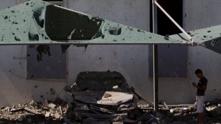 In this photo taken on a government-organized tour a man takes a photo of his car after it was damaged by a NATO airstrike on a building in Tripoli, Libya, Saturday, Aug. 20, 2011. According to people on the scene, the building struck was a private civil engineering office. (AP Photo/Dario Lopez-Mills)