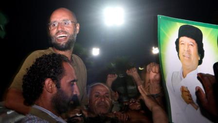 Moammar Gadhafis son, Seif al-Islam, top left, gestures to troops loyal to his father in Tripoli, Libya, Tuesday, Aug. 23, 2011. Seif al-Islam, who was earlier reported arrested by Libyas rebels, turned up early Tuesday morning at the hotel where foreign journalists stay in Tripoli, then took reporters in his convoy on a drive through the city.