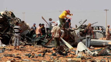 Rebel fighters move around the wreckage of a plane left on the grounds around what used to be Gadhafis 32nd infantry regiments base at Mardun, some 10 kilometers from the outskirts of Ban Walid, Libya, Wednesday, Sept. 7, 2011.
