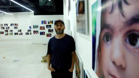 Photographer Danny Goldfield pose among his exhibition of photographs celebrating New York children from over 160 different countries on Wednesday, Sept. 21, 2011 at the Park 51mosque gallery space in New York. (AP Photo/Bebeto Matthews)