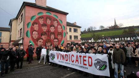 Relatives of the Bloody Sunday victims pause beside a mural of the victims during the last Bloody Sunday March in Londonderry, Northern Ireland, Sunday, Jan. 30, 2011. The Bloody Sunday remembrance march took place through the streets of Derry for the last time. The marchers started from the Creggan area walking behind a banner carried by the families which read vindicated.They completed the route begun in 1972 - the march usually stops at Free Derry Corner, but instead went all the way to the Guildhall. Organisers said they believe the annual event should come to an end following the publication of the Saville Report. A statement said the protest was no longer necessary after the inquiry exonerated those who died in the 1972 Bloody Sunday shooting.