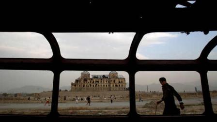 Seen through the wreckage of a bus left on the roadside, an Afghan youth, right, looks on while others play football around the former palace of Afghan King Darul Aman, which was destroyed during the civil war, in Kabul, Afghanistan, Friday, Oct. 28, 2011.